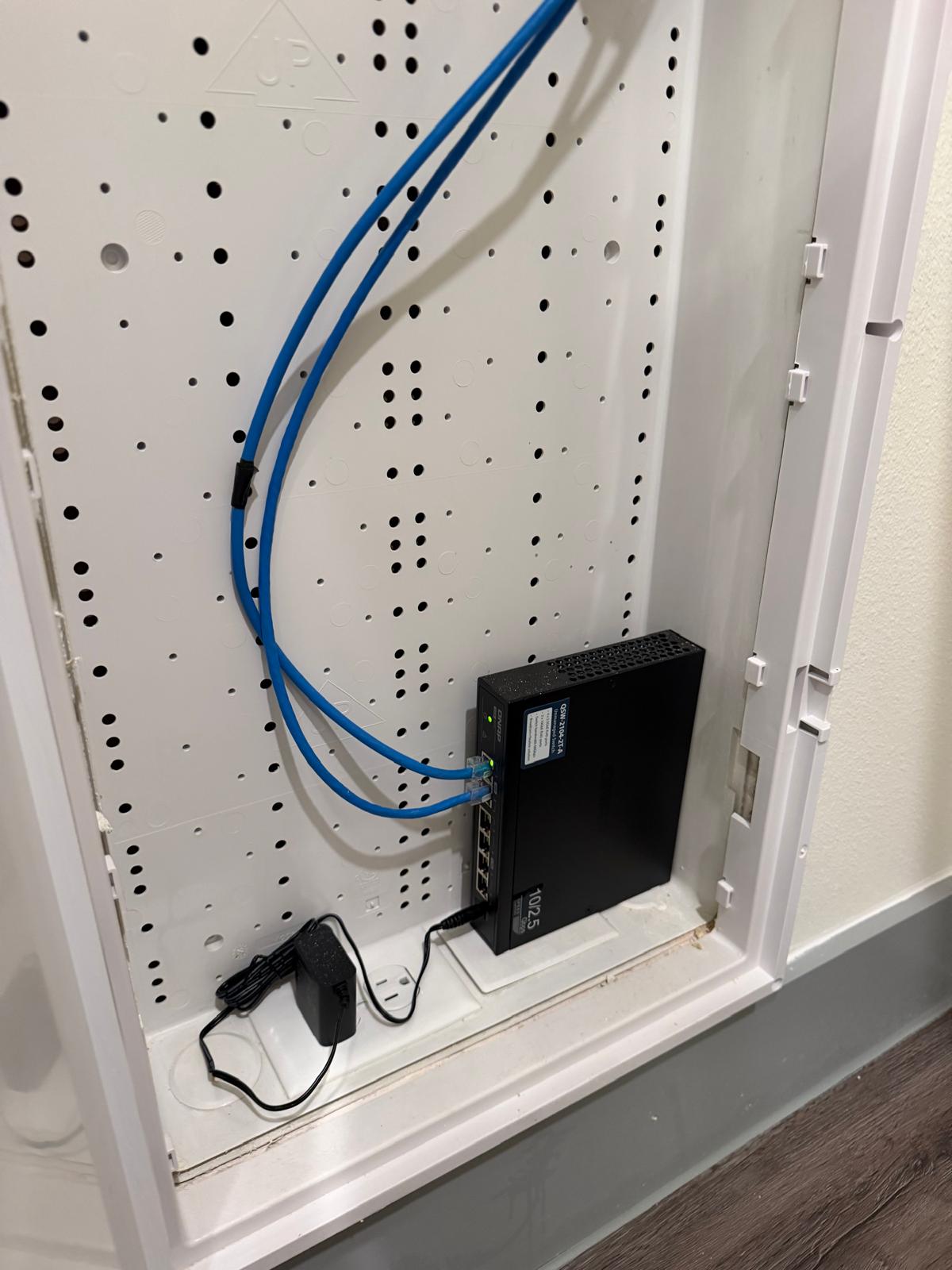 Inside the open media panel: a compact network switch, blue Ethernet runs, and power