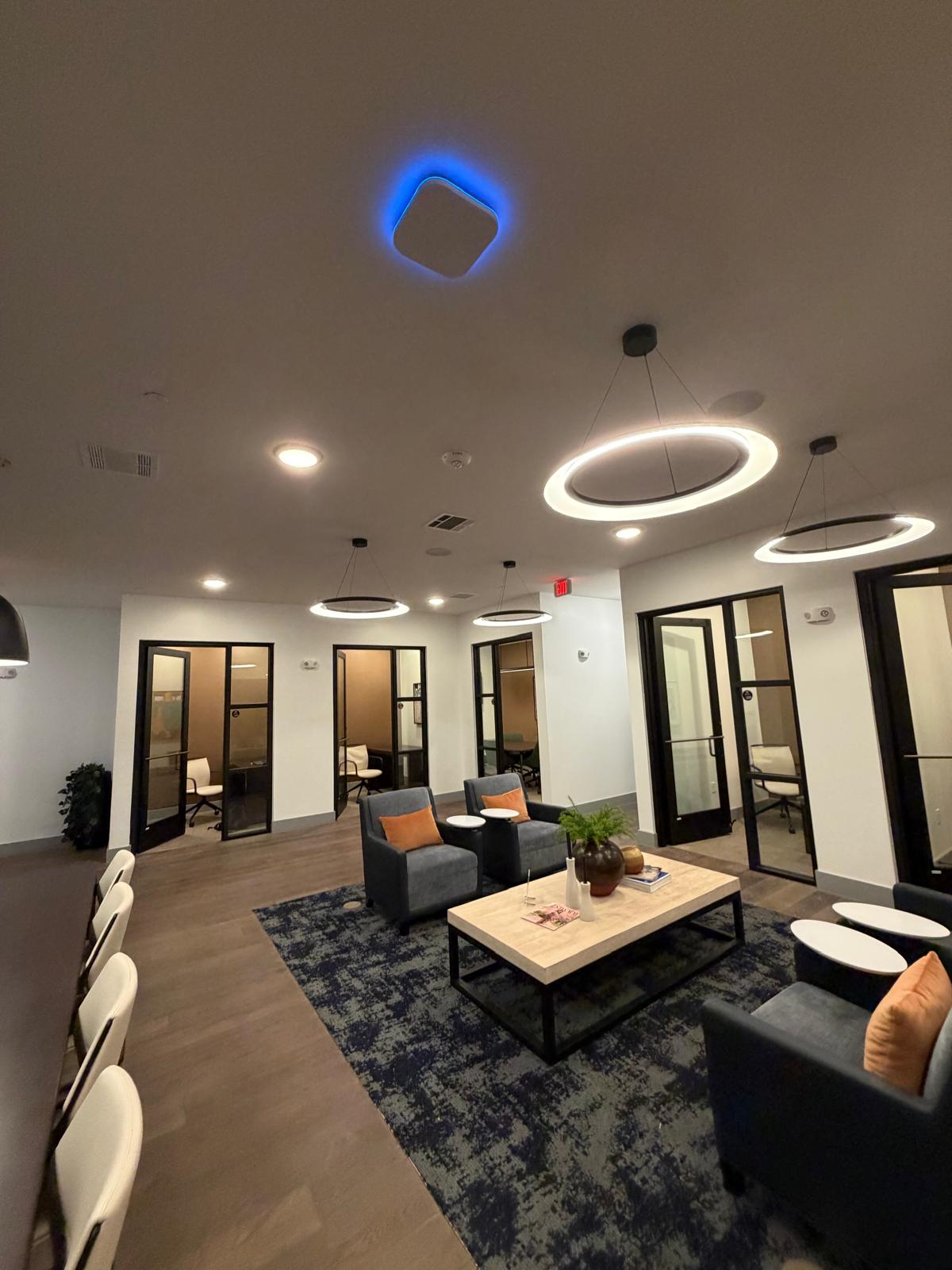 A WiFi 7 access point glowing blue on the ceiling of the coworking lounge at The Anderson